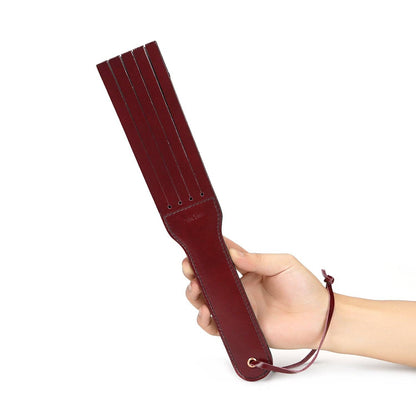 Hand holding wine-red paddle, ready for impact play
